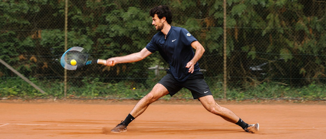 tennis player sliding and hitting a pressurized tennis ball thanks to the Bounce Tube